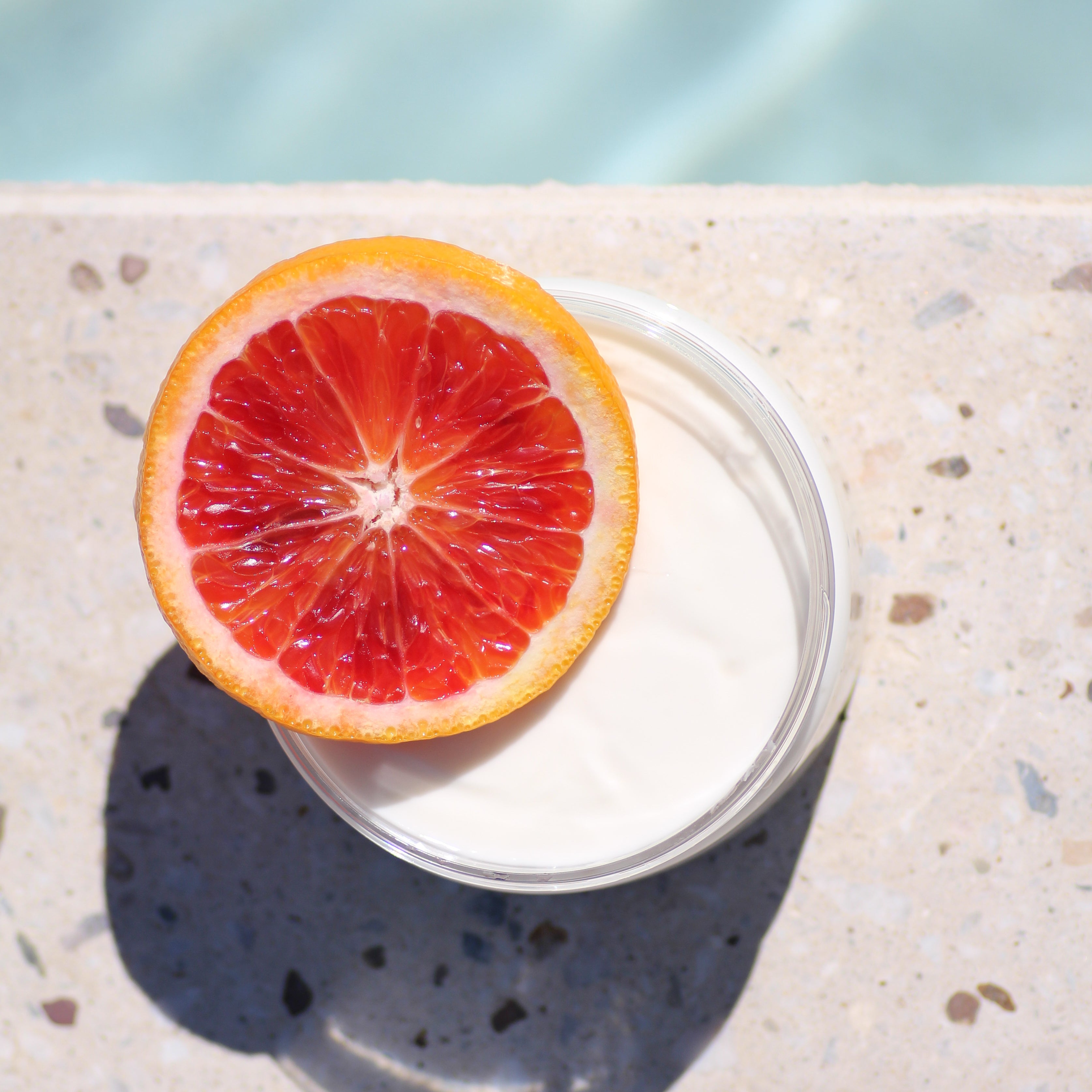 Blood Orange slice on Santo Cabo body lotion near a pool