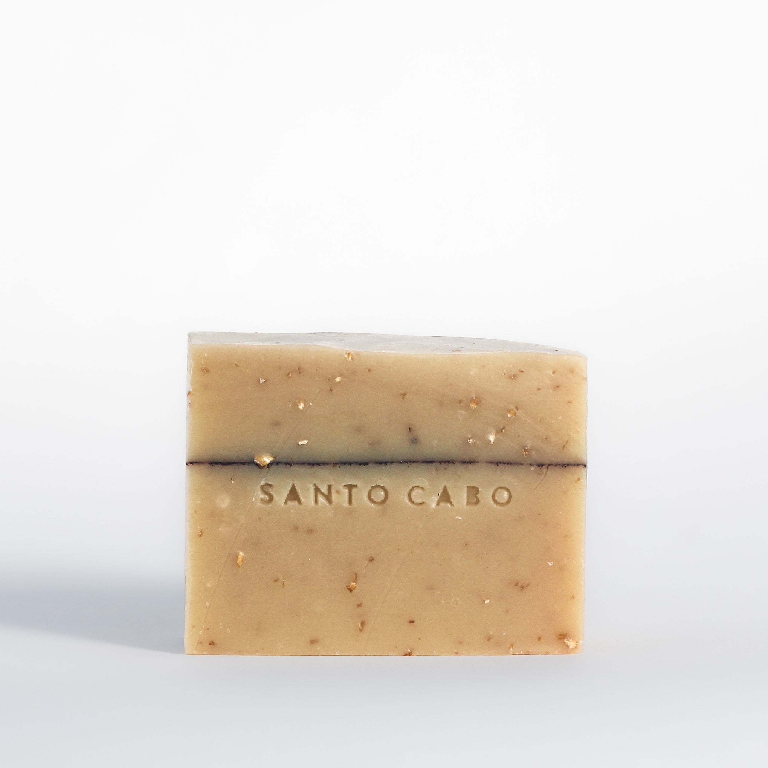 Single bar of handmade Cinnamon Oat Soap bar with cinnamon detail line, flecks of hand ground oats and stamped with Santo Cabo logo.